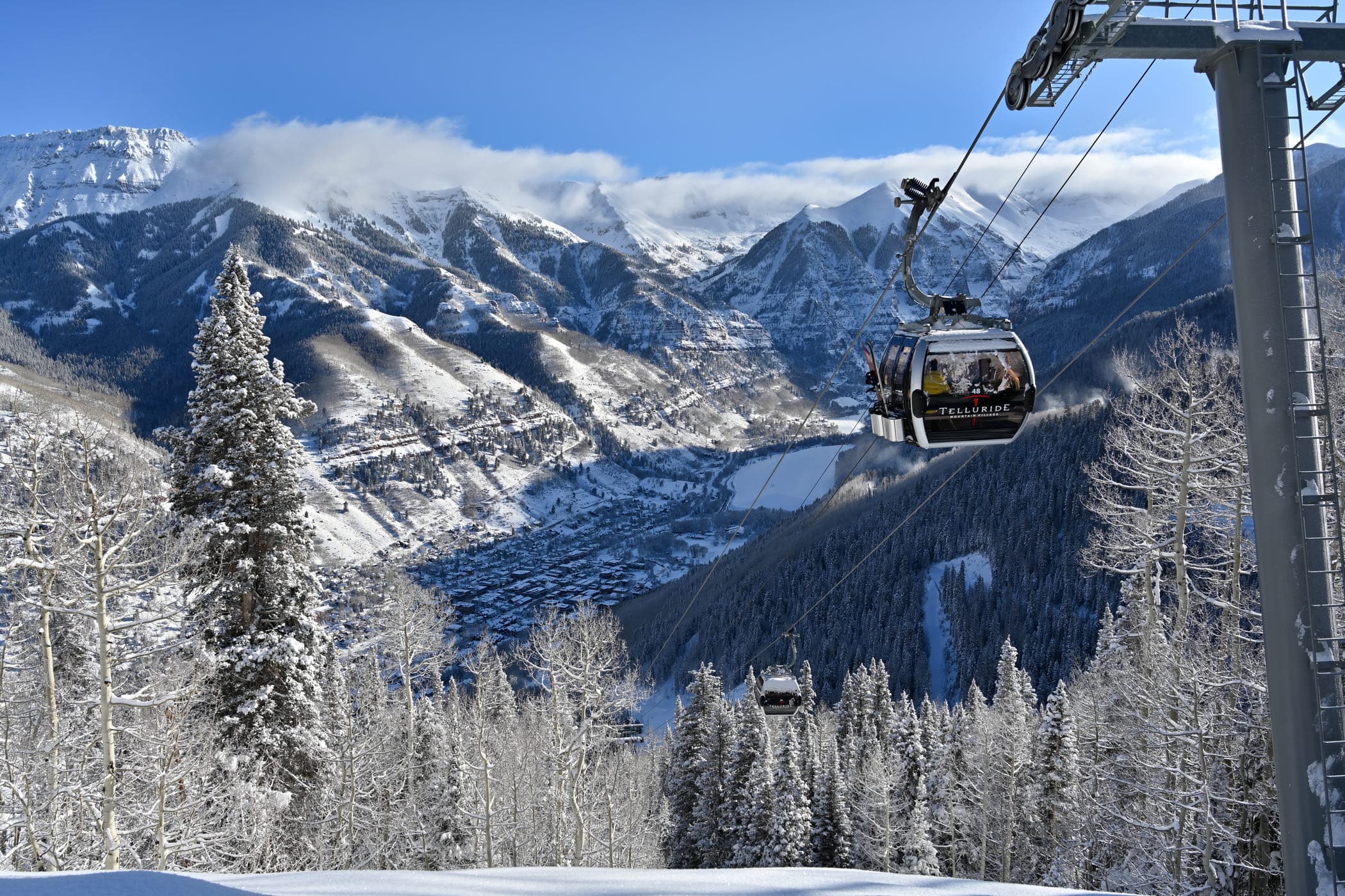 A gondola cabin above the valley with the San Juans behind.