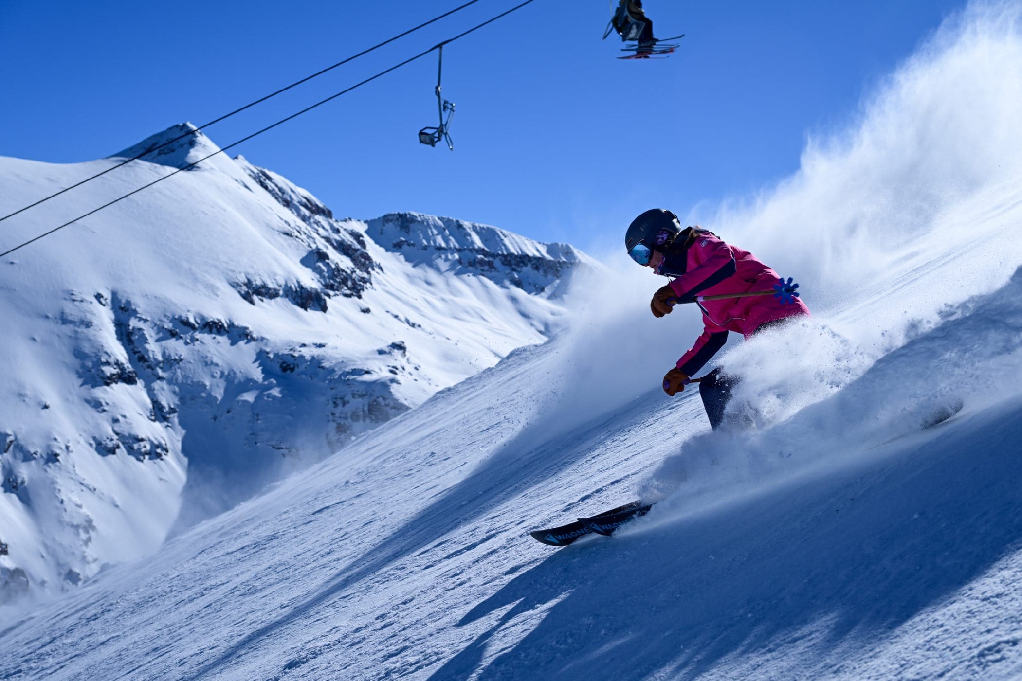 A skier in the air off the top of a snowy pitch.